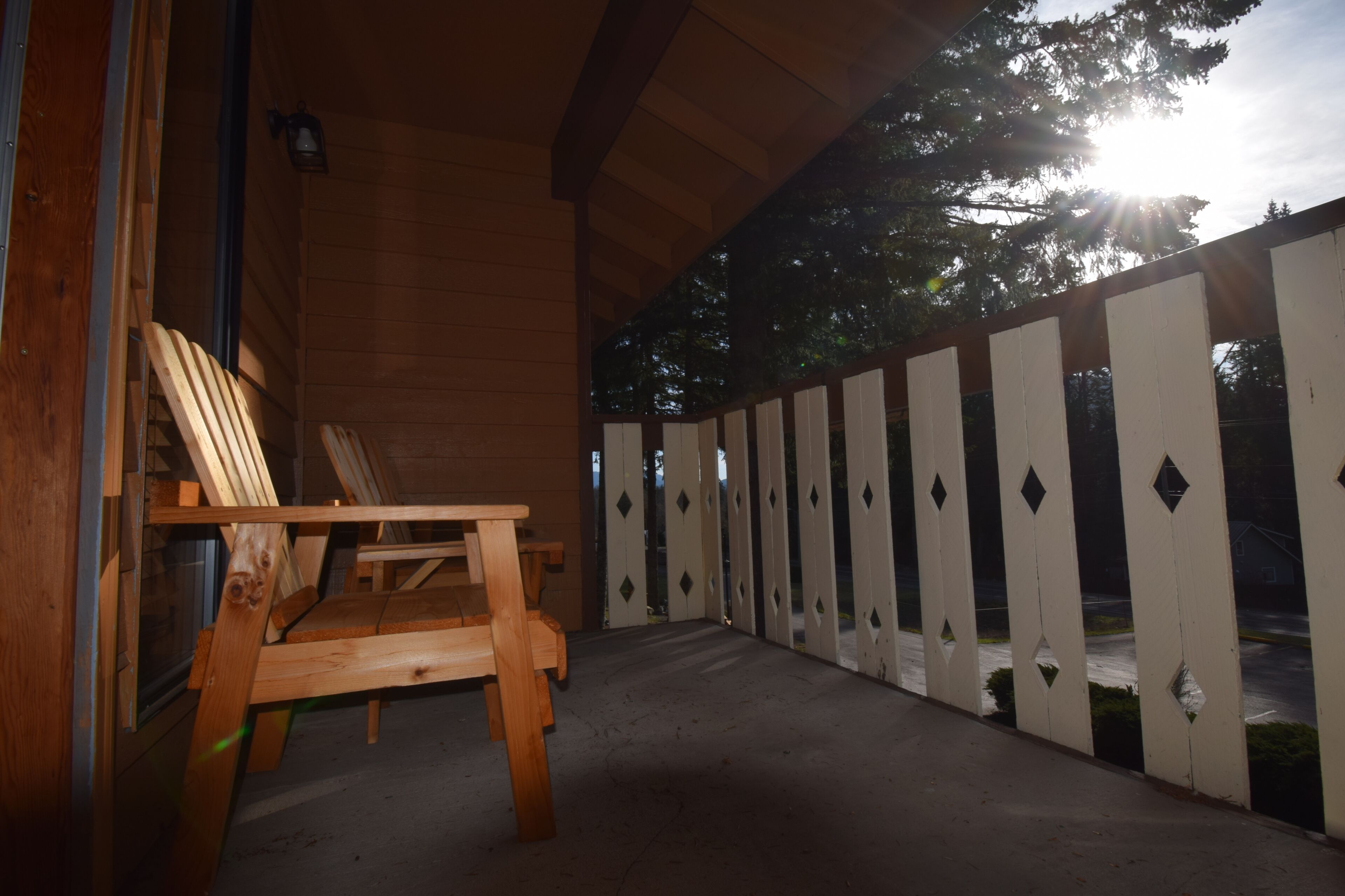 A wooden deck with a chair, a fence, and a building in the background.