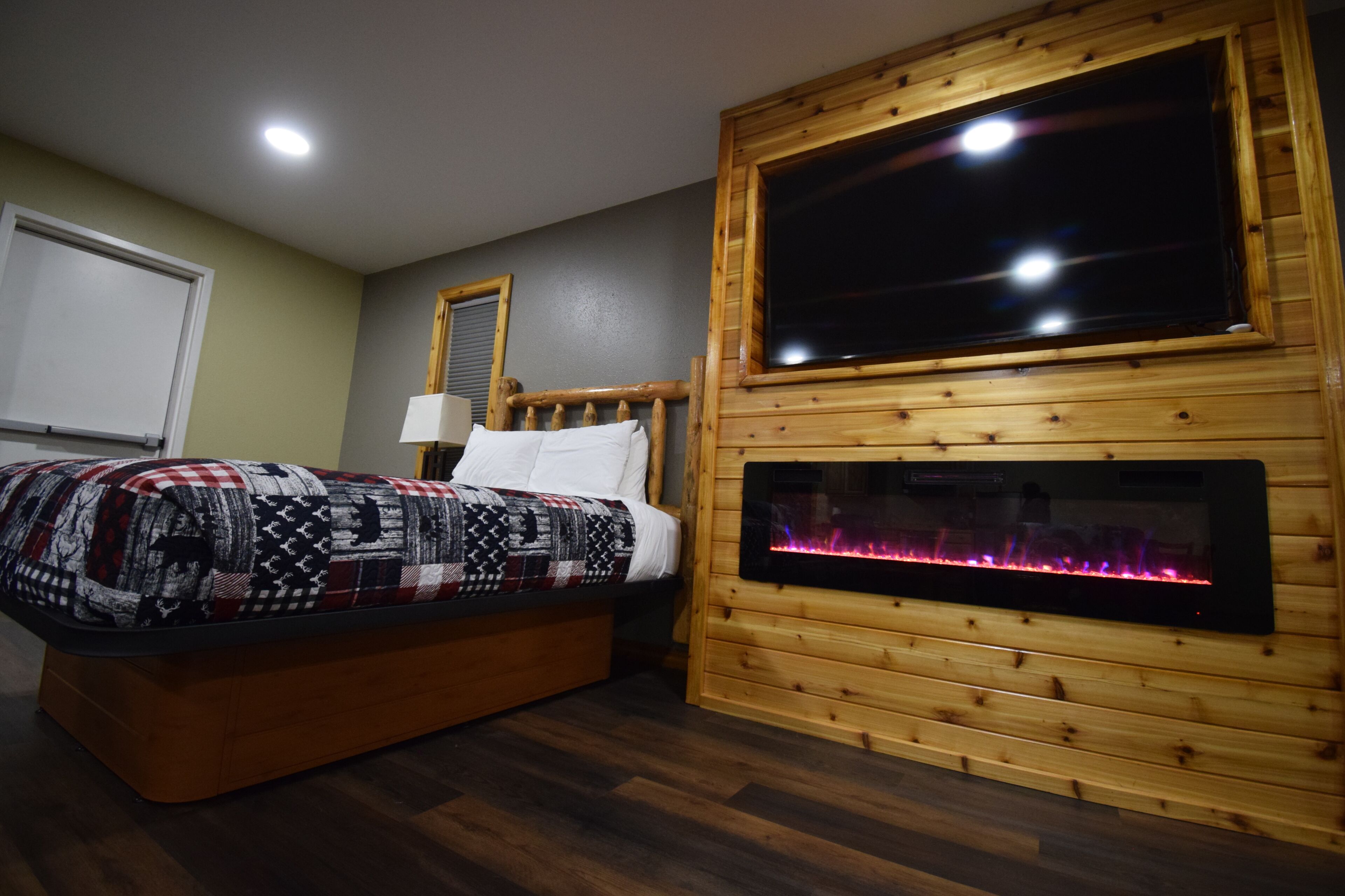 Una habitación con cama, chimenea y un ventanal grande.