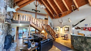 A spacious lodge with a wooden staircase, a stone fireplace, and a cozy seating area. - Nisqually Lodge (Ashford)