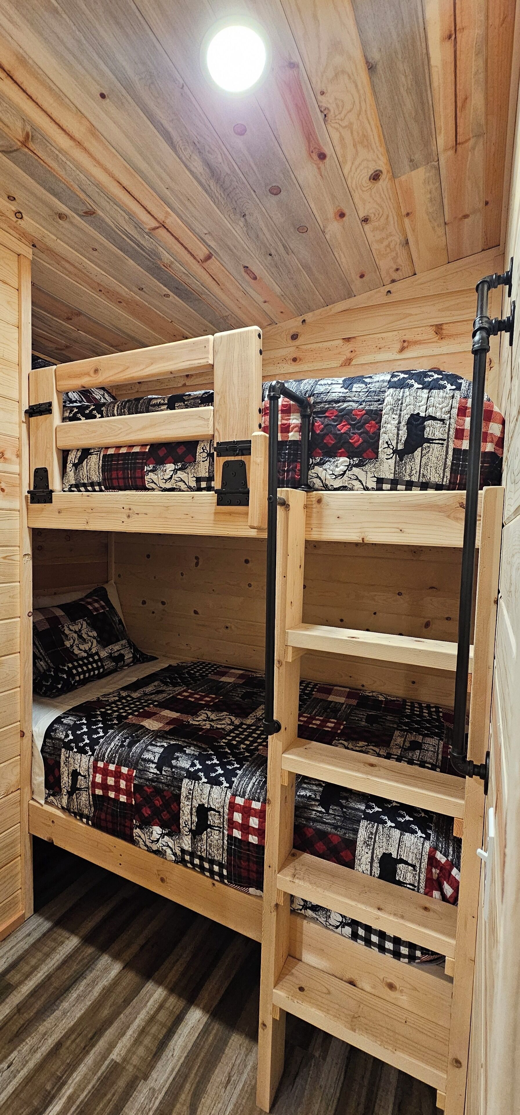 A wooden bunk bed with a ladder, multiple pillows, and a quilted blanket.
