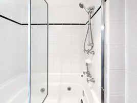 Un baño moderno con cabina de ducha de vidrio, bañera blanca y accesorios de cromo.