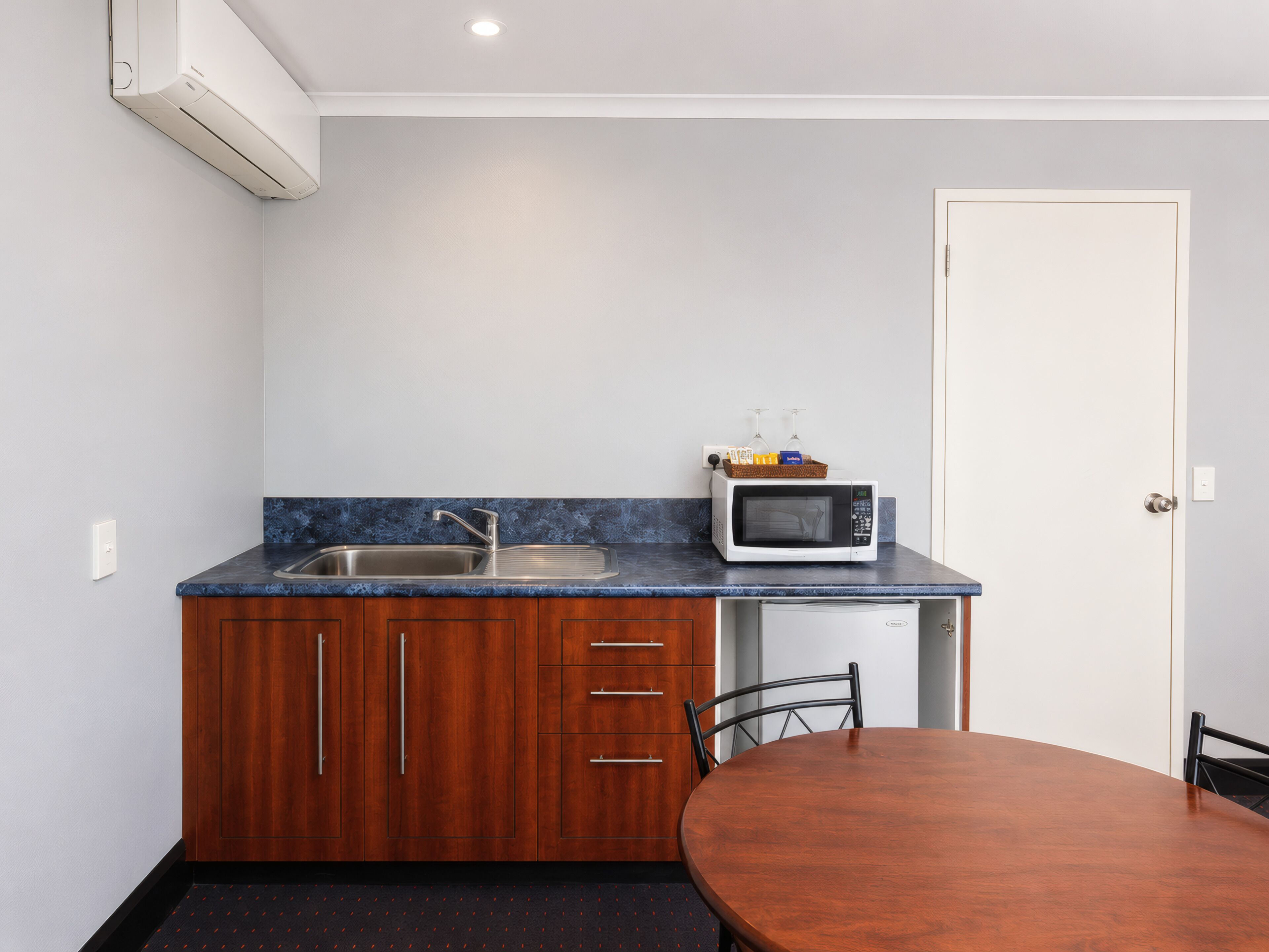 A compact kitchen with a sink, a microwave, and a small refrigerator.
