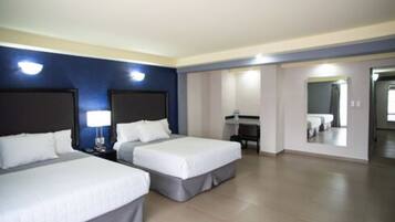 A hotel room with two beds, a desk, and a mirror.