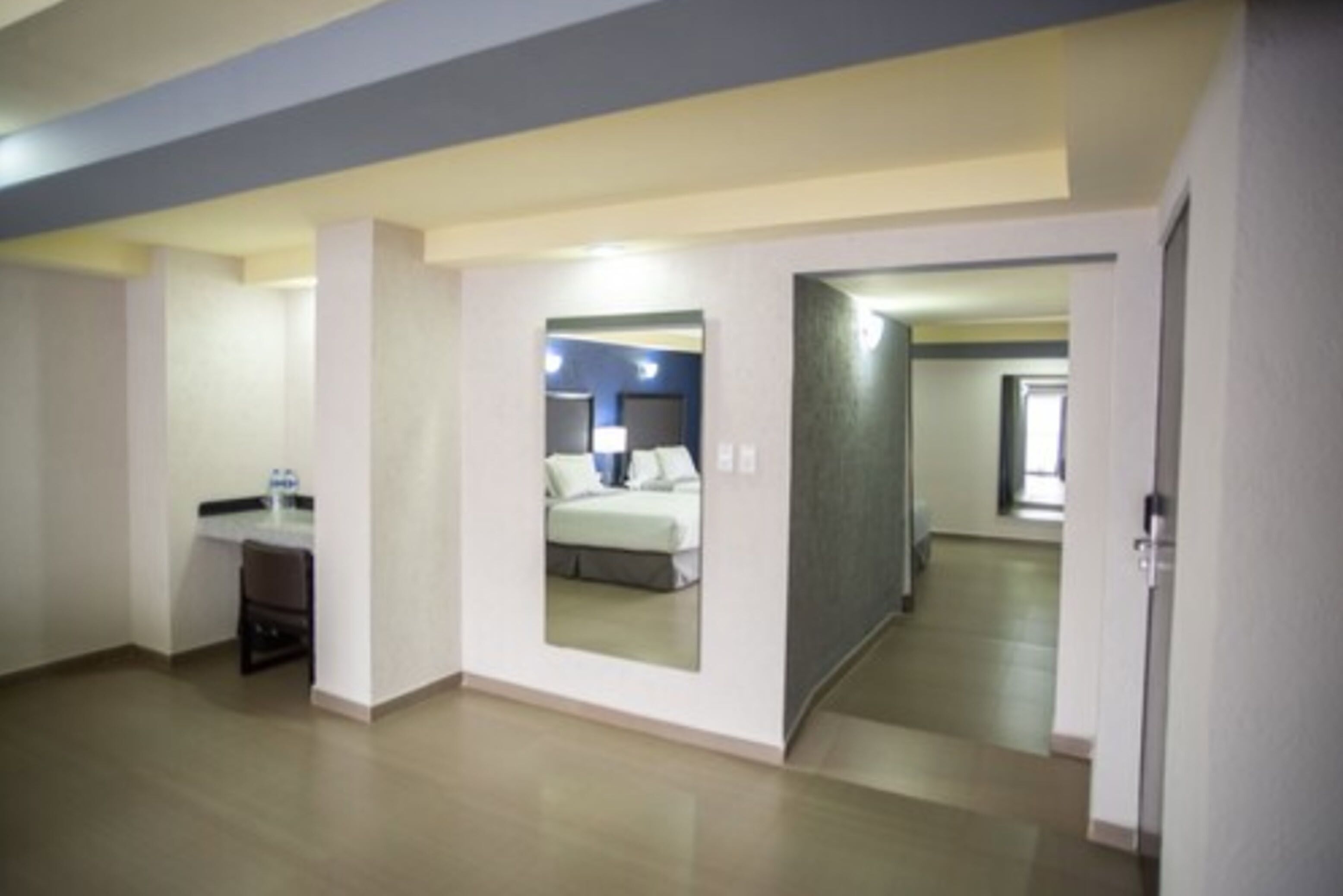 Una habitación de hotel con una cama, un escritorio y un espejo.
