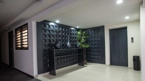 A modern hallway with a patterned wall, a potted plant, and a door. - Hotel Ha (Orizaba)