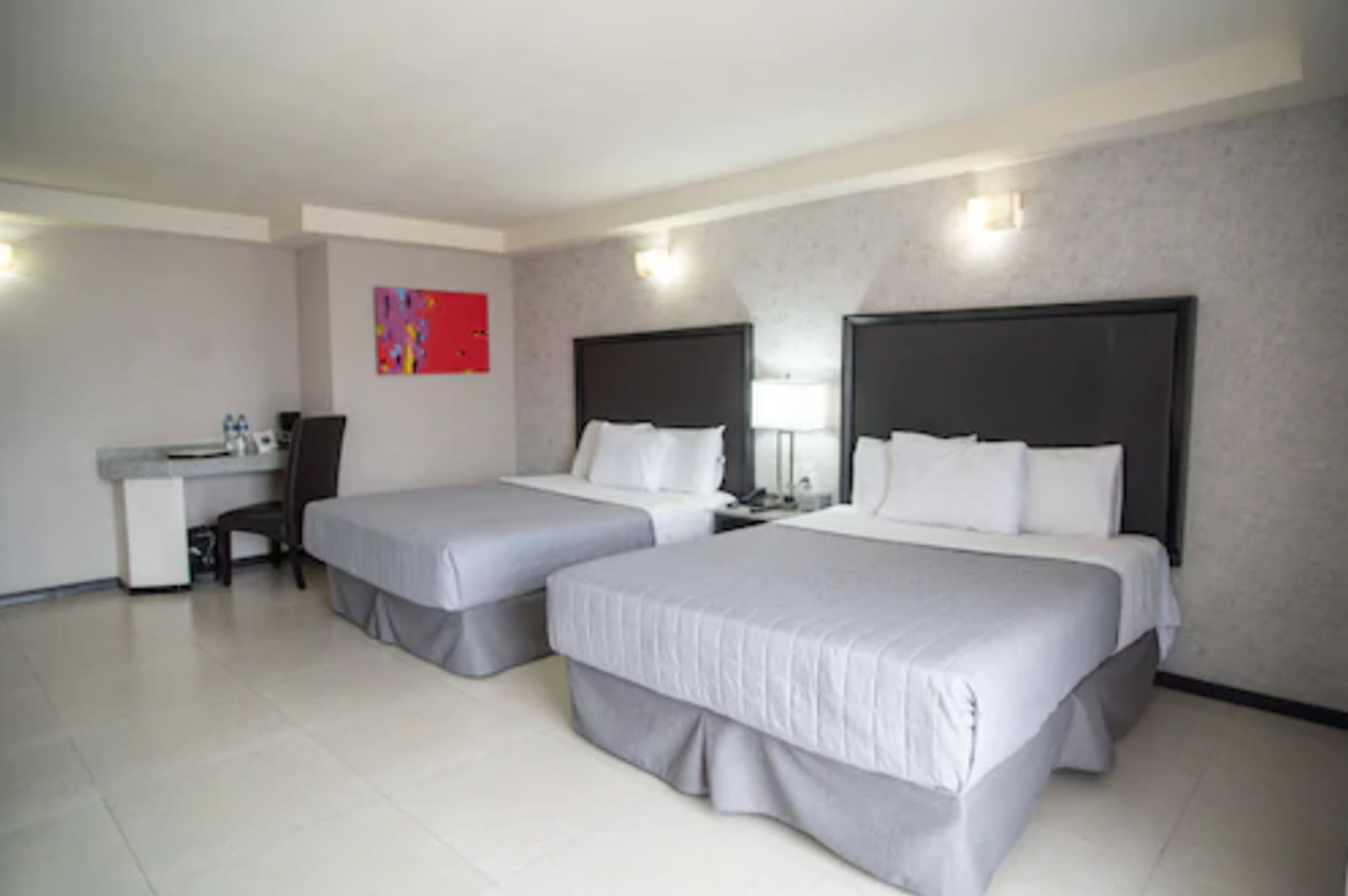 Une chambre d’hôtel avec deux lits, un bureau, une chaise et une petite table.