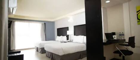 Una habitación de hotel con dos camas, un escritorio, una silla y una ventana.
