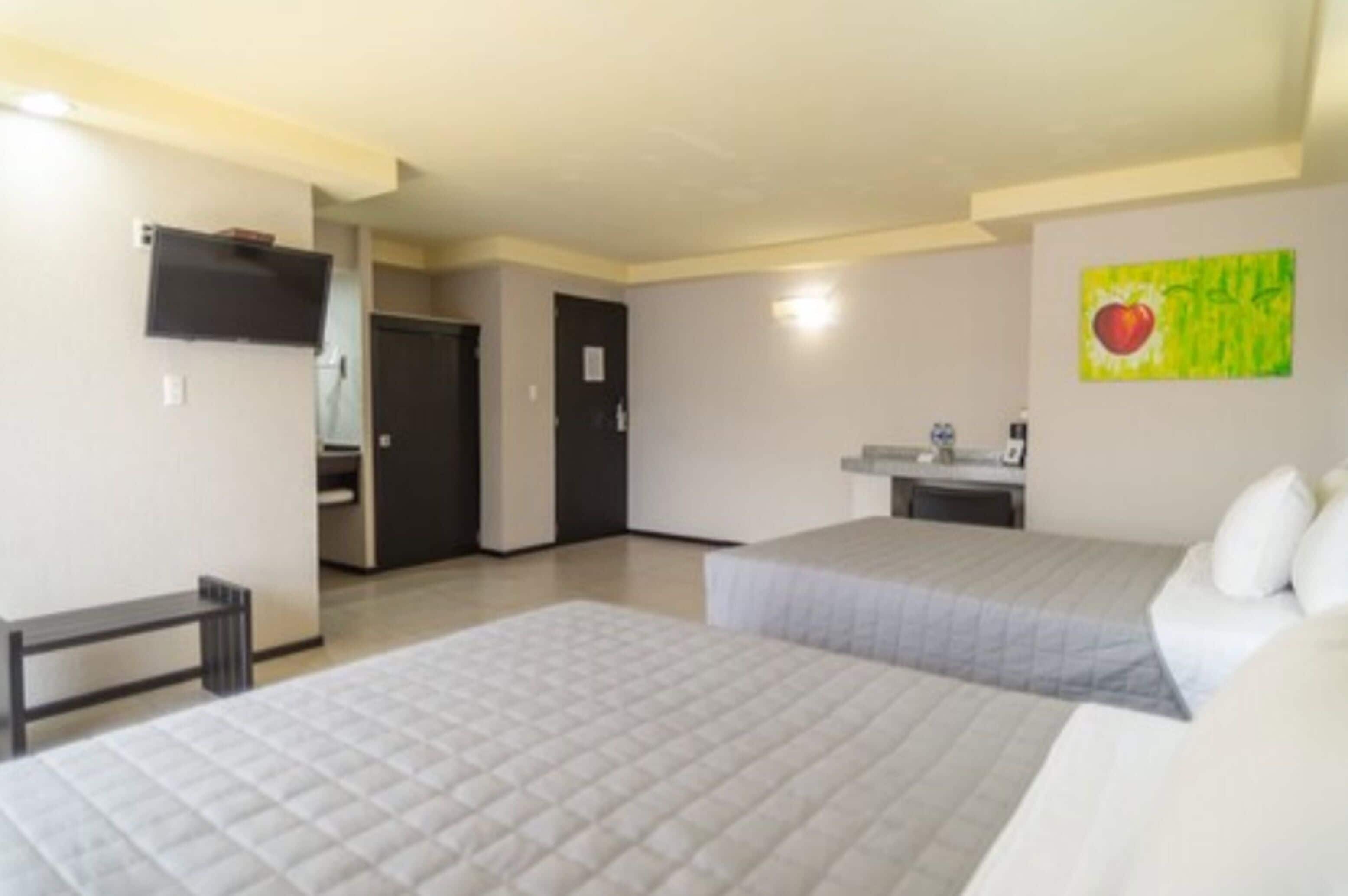 A hotel room with two beds, a small desk, a TV, and a painting on the wall.