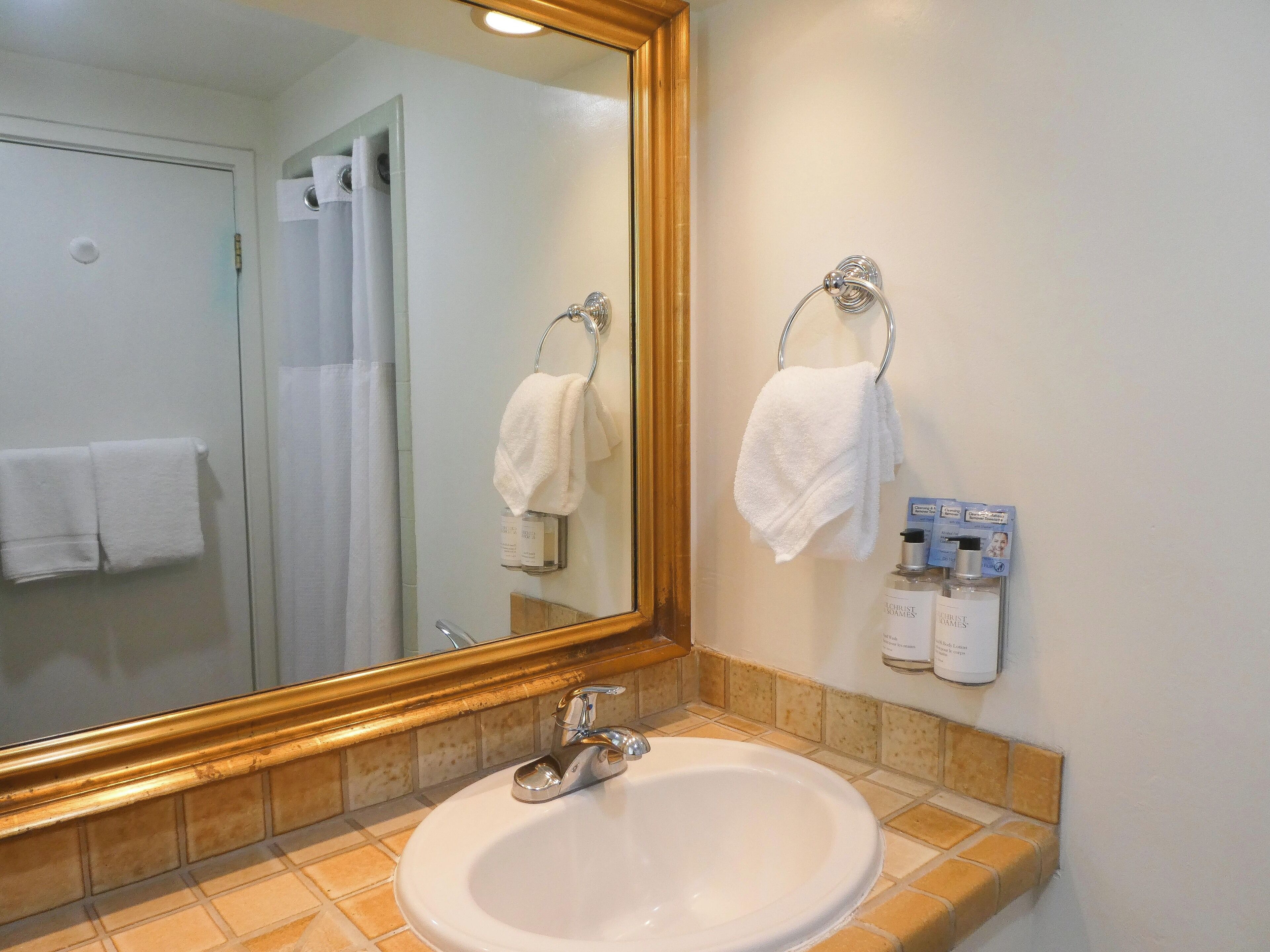 Un baño con lavamanos, espejo y perchero para toallas.