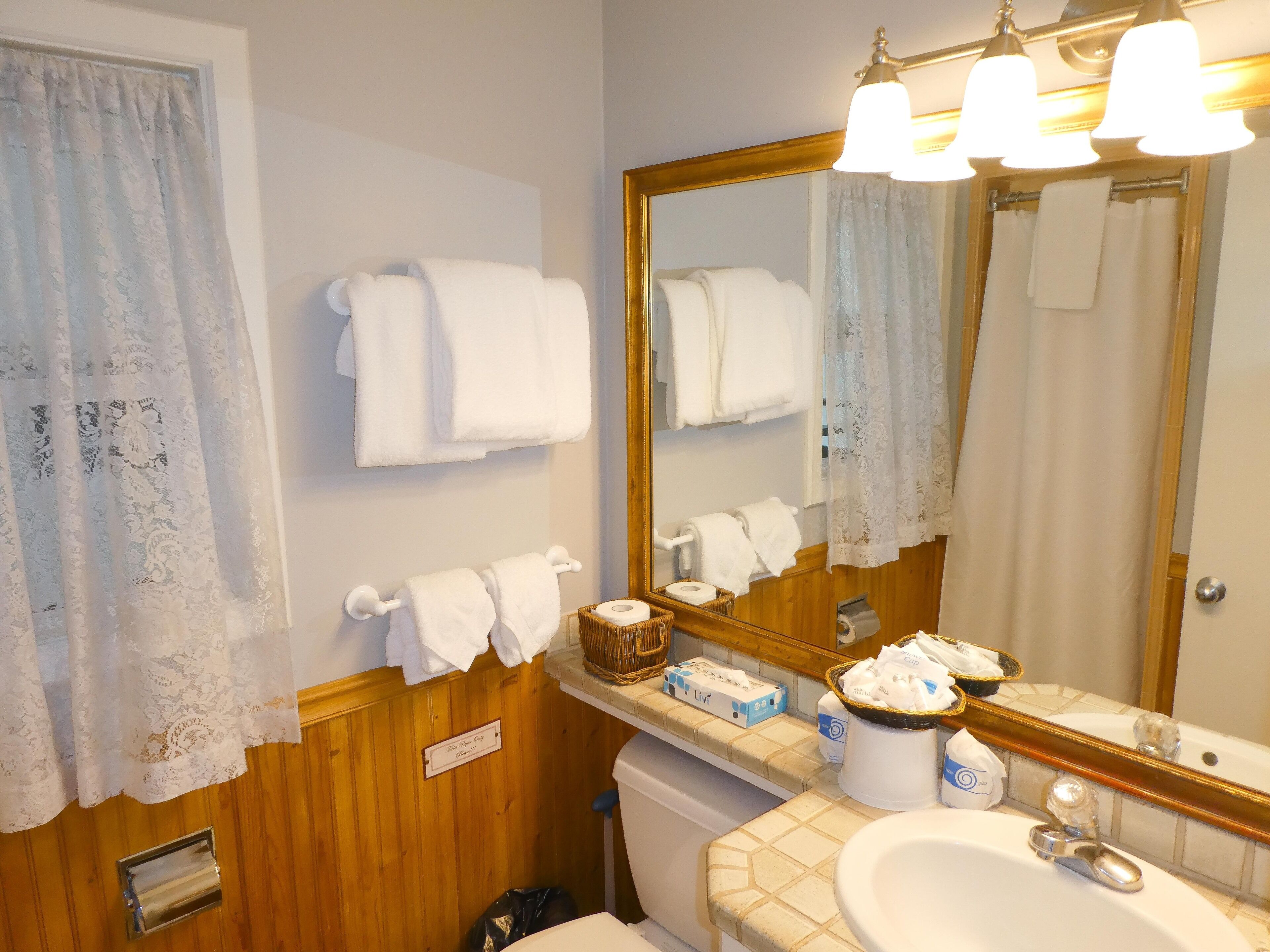 Une salle de bain avec un meuble-lavabo en bois, un évier, un miroir et des serviettes accrochées au mur.