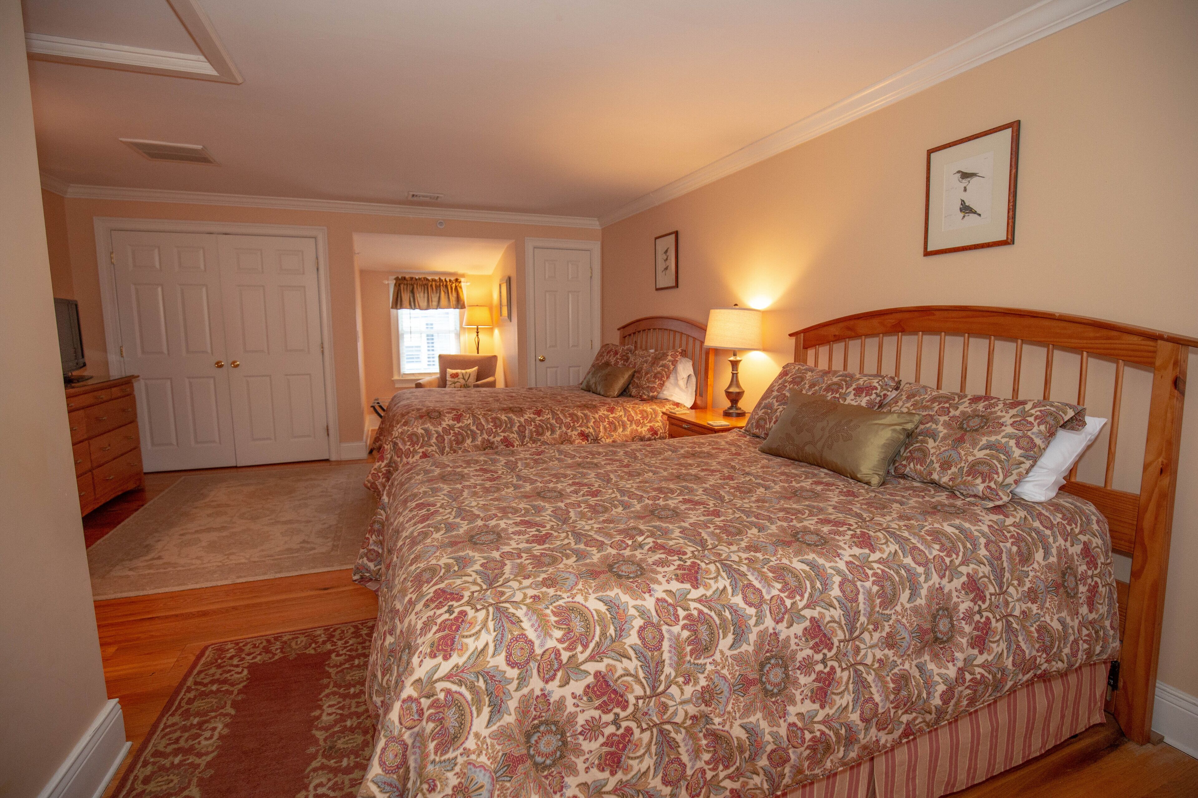 A bedroom with a large bed, a dresser, and a door leading to another room.