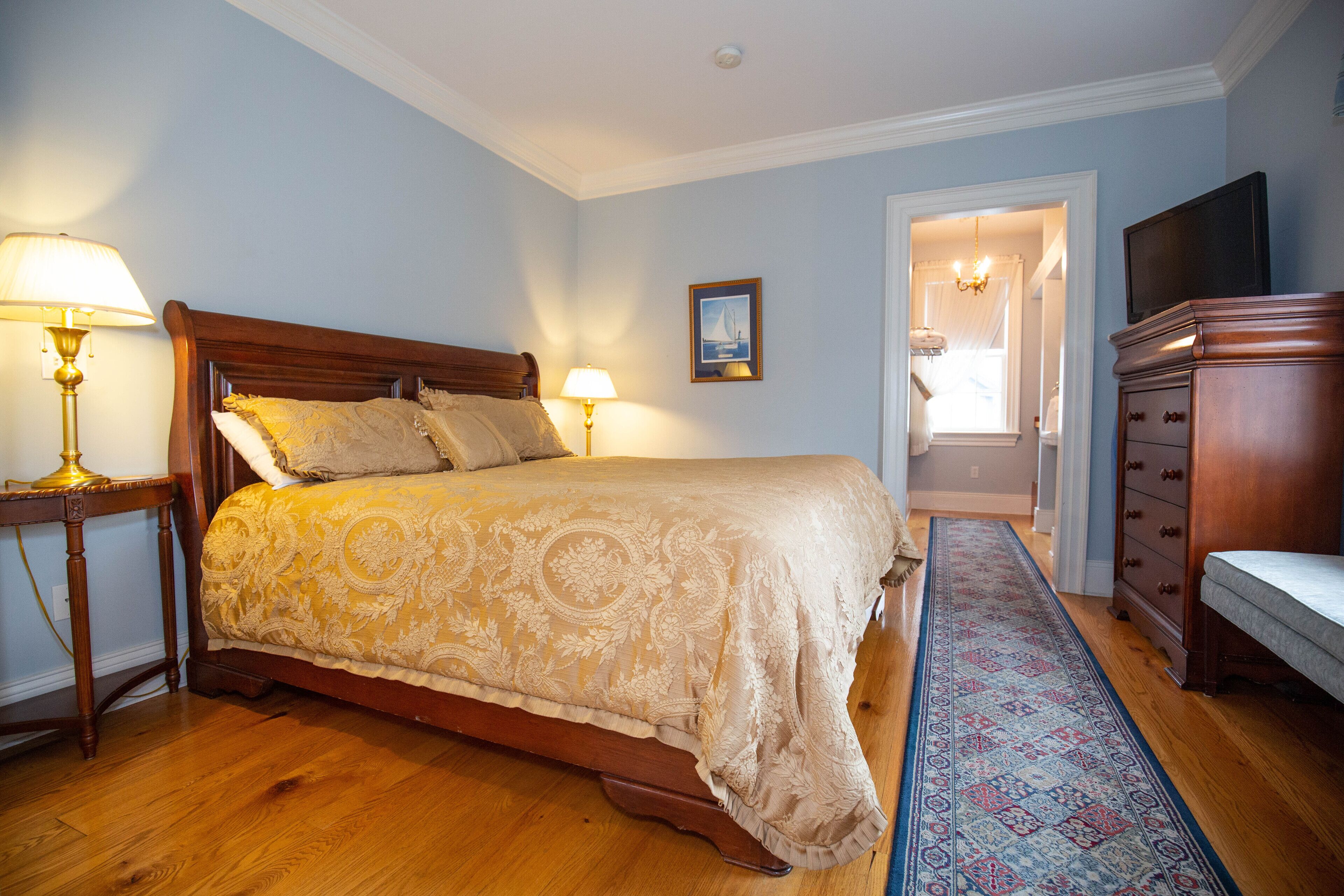 Une chambre avec un grand lit, deux lampes de chevet, une commode en bois et un tapis à motifs.