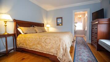 A bedroom with a large bed, two bedside lamps, a wooden dresser, and a patterned rug.