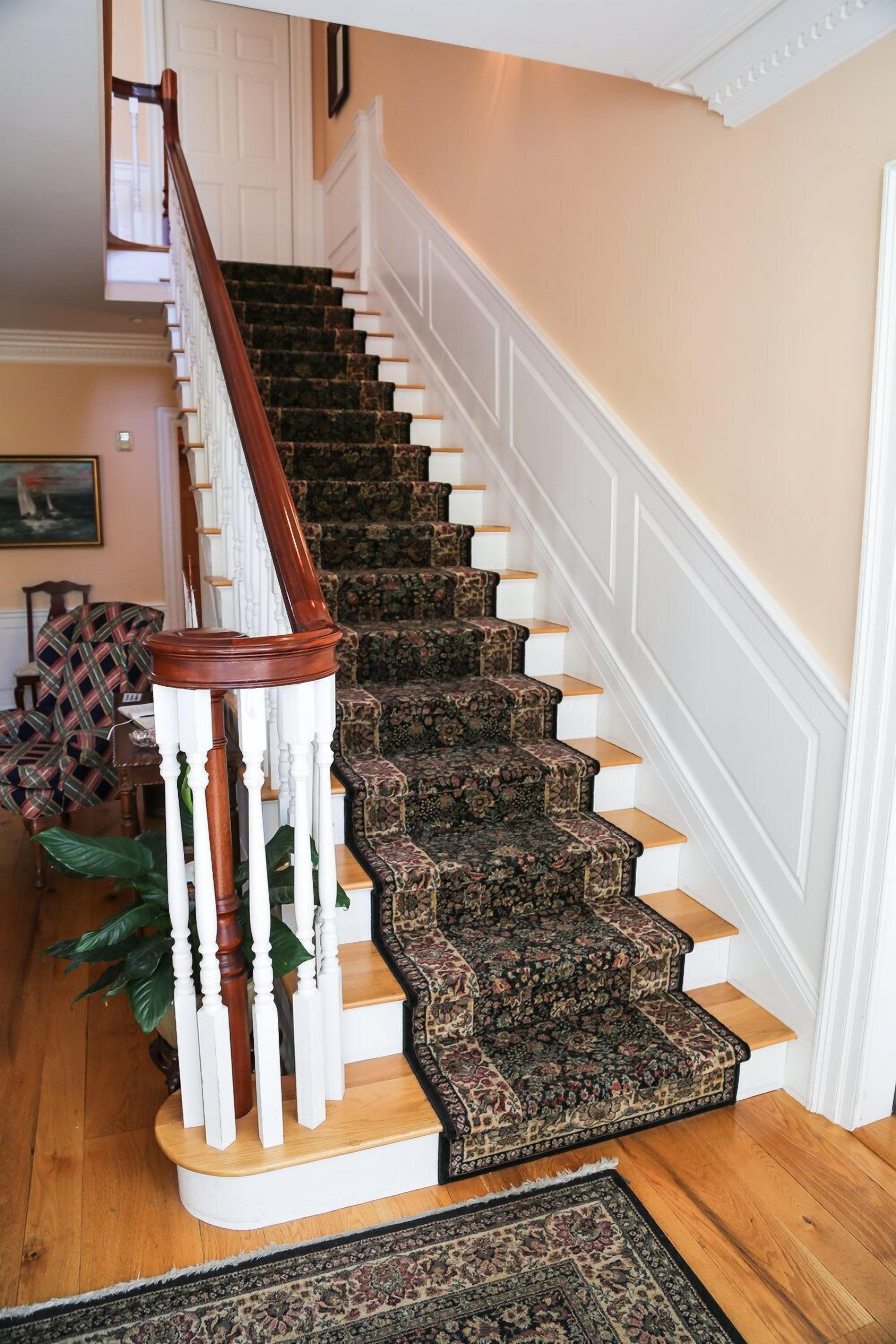 Una escalera con barandilla de madera y peldaños alfombrados.