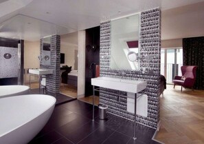A modern bathroom with a large white bathtub, a mirror, and a wall of decorative tiles. - Hotel Oleana (Bergen)