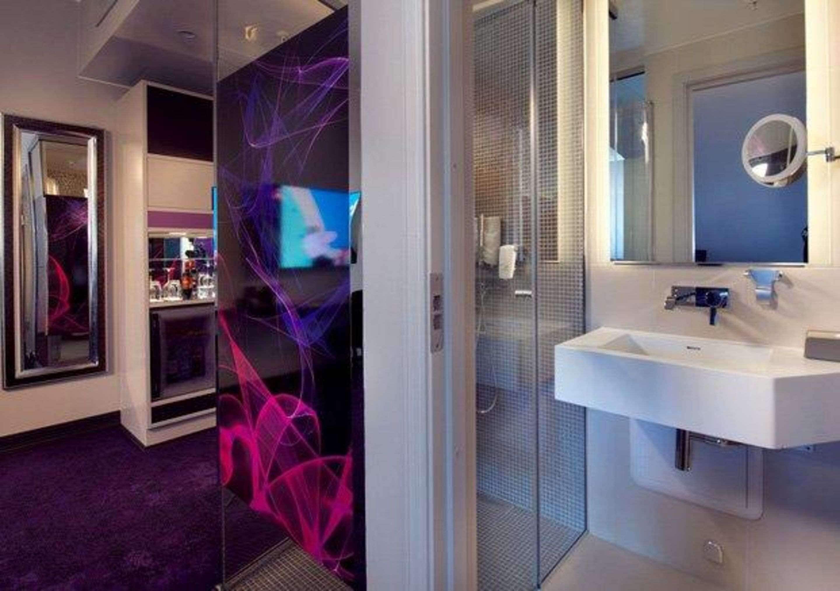 A modern bathroom with a glass shower enclosure, a white sink, and a mirror.