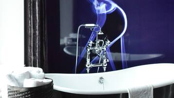 Une salle de bain avec une baignoire noire, une serviette blanche et un rouleau de mouchoirs posé sur un porte-serviettes noir.