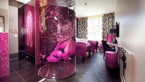 A modern spa room with a large glass enclosure, a massage table, and a reception area with a TV. - Hotel Oleana (Bergen)