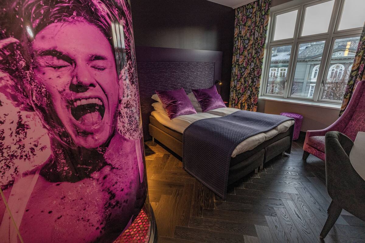 Un dormitorio con una cama, una silla y un cartel grande en la pared.