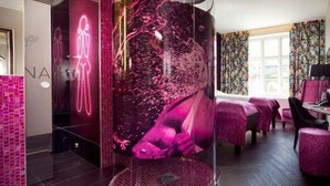Une chambre d’hôtel moderne dotée d’un élément décoratif central en forme de sphère, d’un coin salon privatif et offrant une vue sur la ville grâce à de grandes fenêtres.