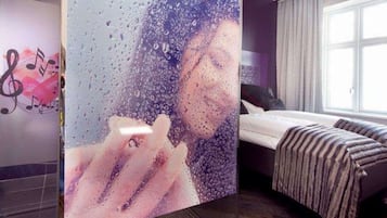 A hotel room with a bed, a window, and a wall with a musical note design.