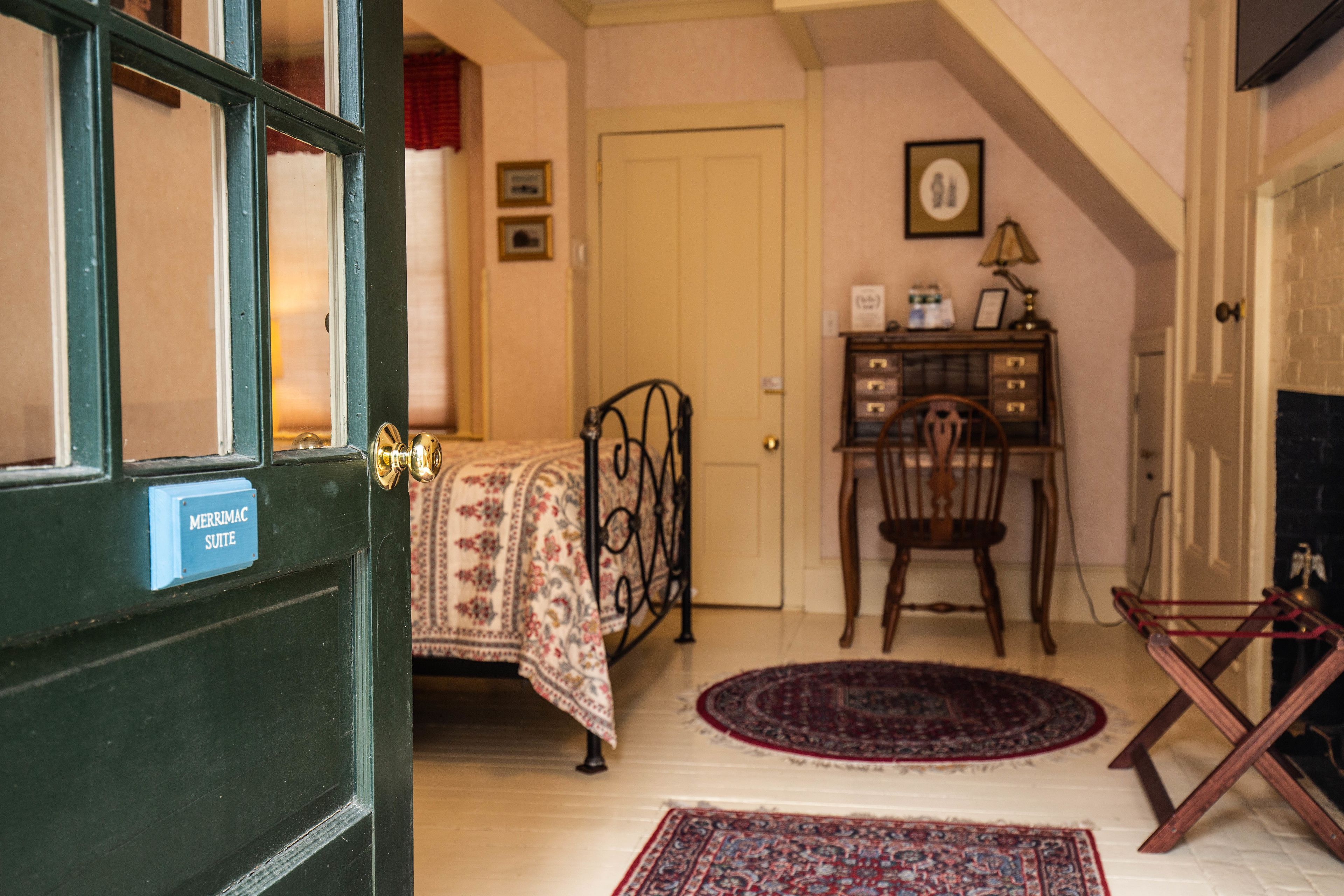 A room with a bed, a desk, a chair, and a fireplace.