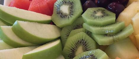 Una bandeja de frutas con diversas frutas cortadas, como sandía, kiwi, uvas y melón.