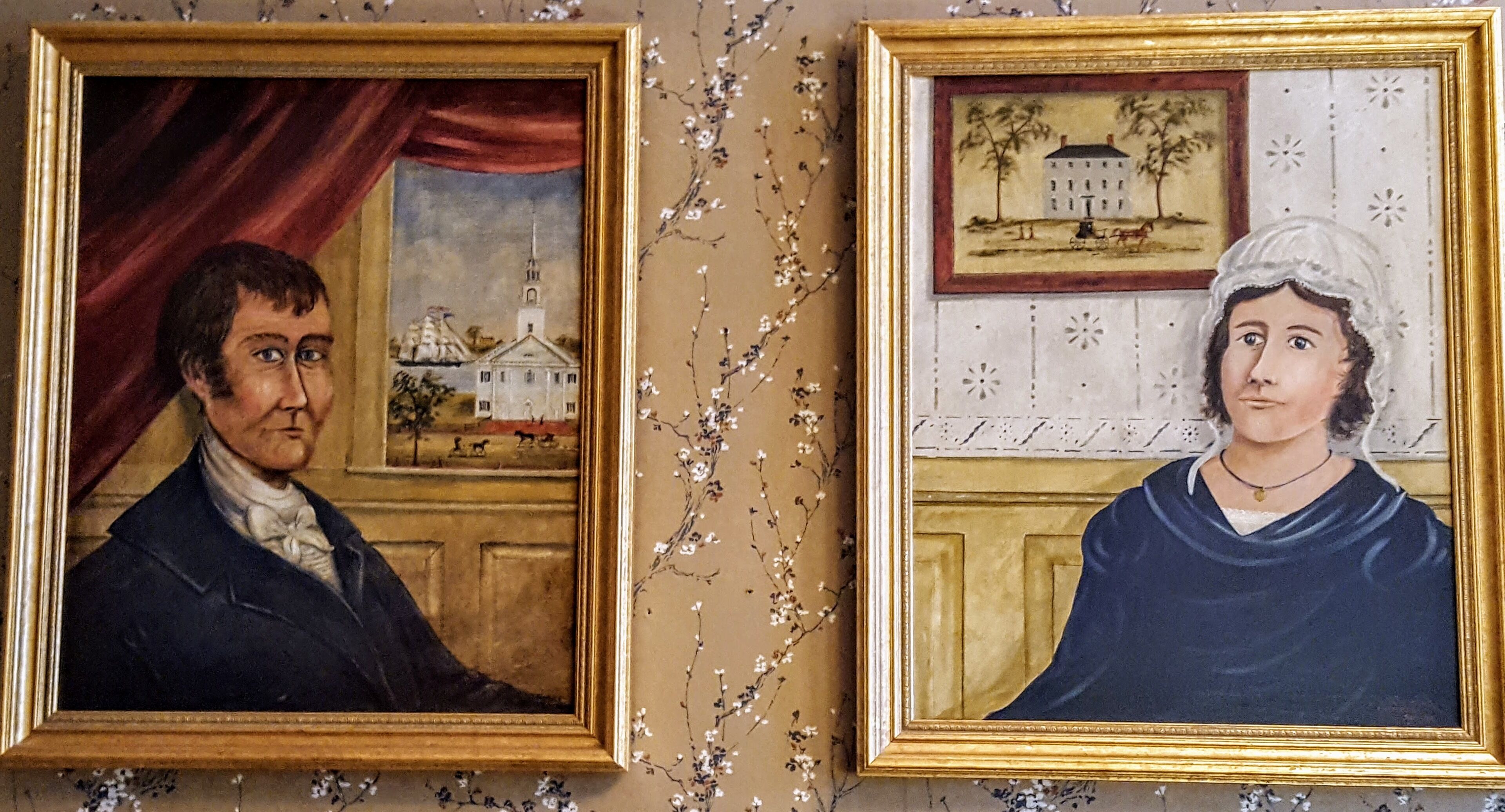 Two framed portraits on a wall with a floral pattern.