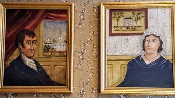 Two framed portraits on a wall with a floral pattern.