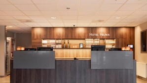 A reception desk with a wooden backdrop and a sign that reads 'Hotel Helma.' - Home Hotel Helma (Mo-I-Rana)