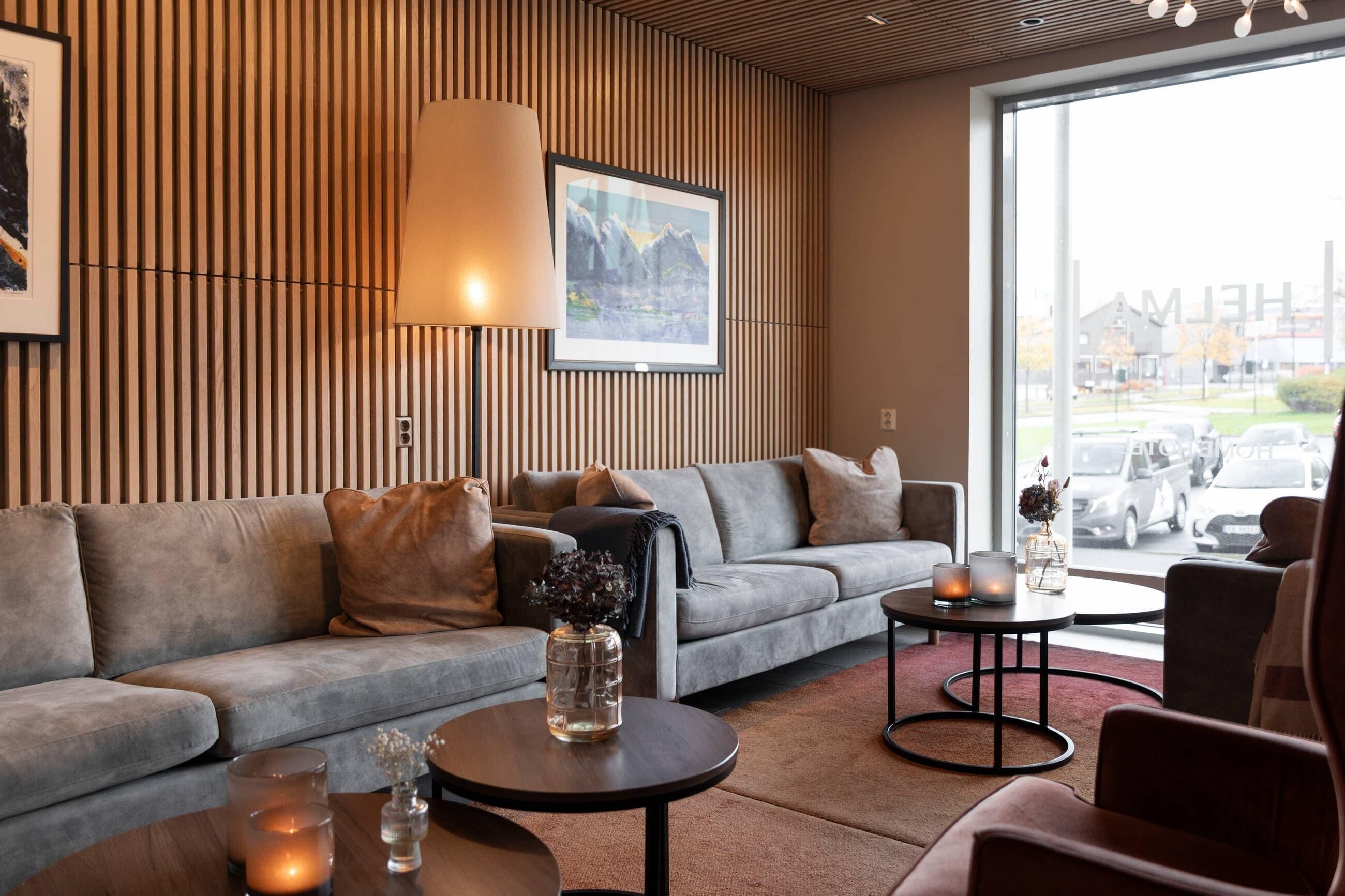 A modern living room with a sofa, two coffee tables, and a large window with a view of a parking lot.