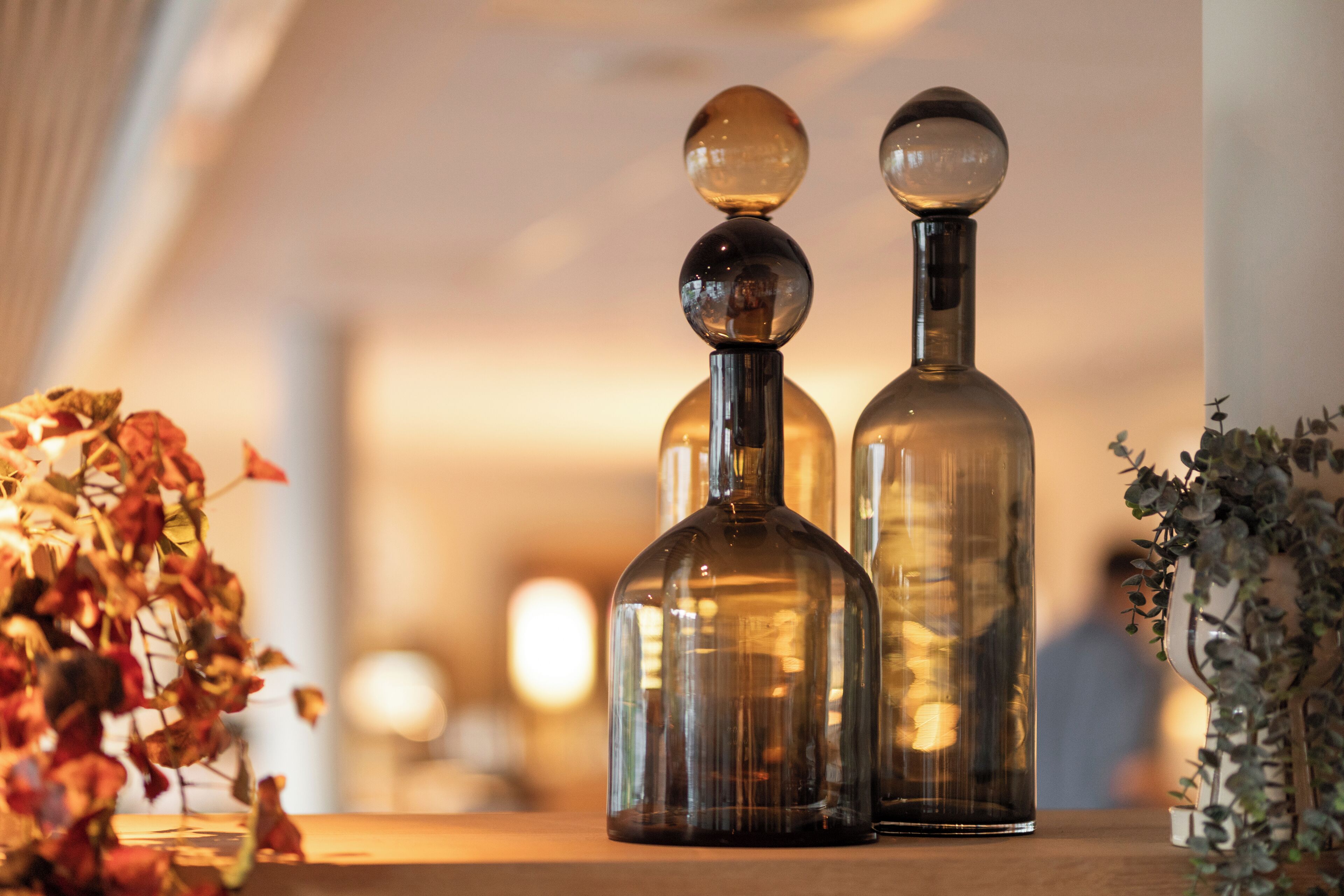 Three glass decanters on a wooden surface with a blurred background.