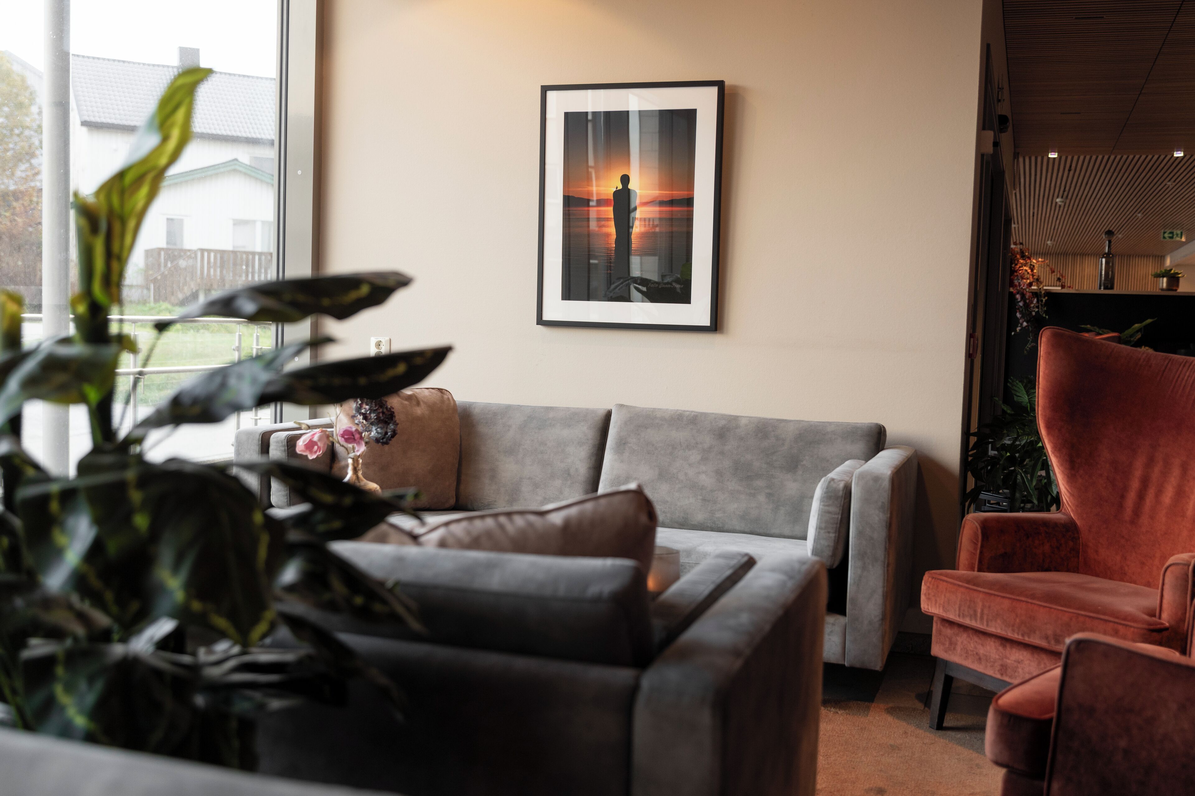 A living room with a grey sofa, a red armchair, and a framed picture on the wall.