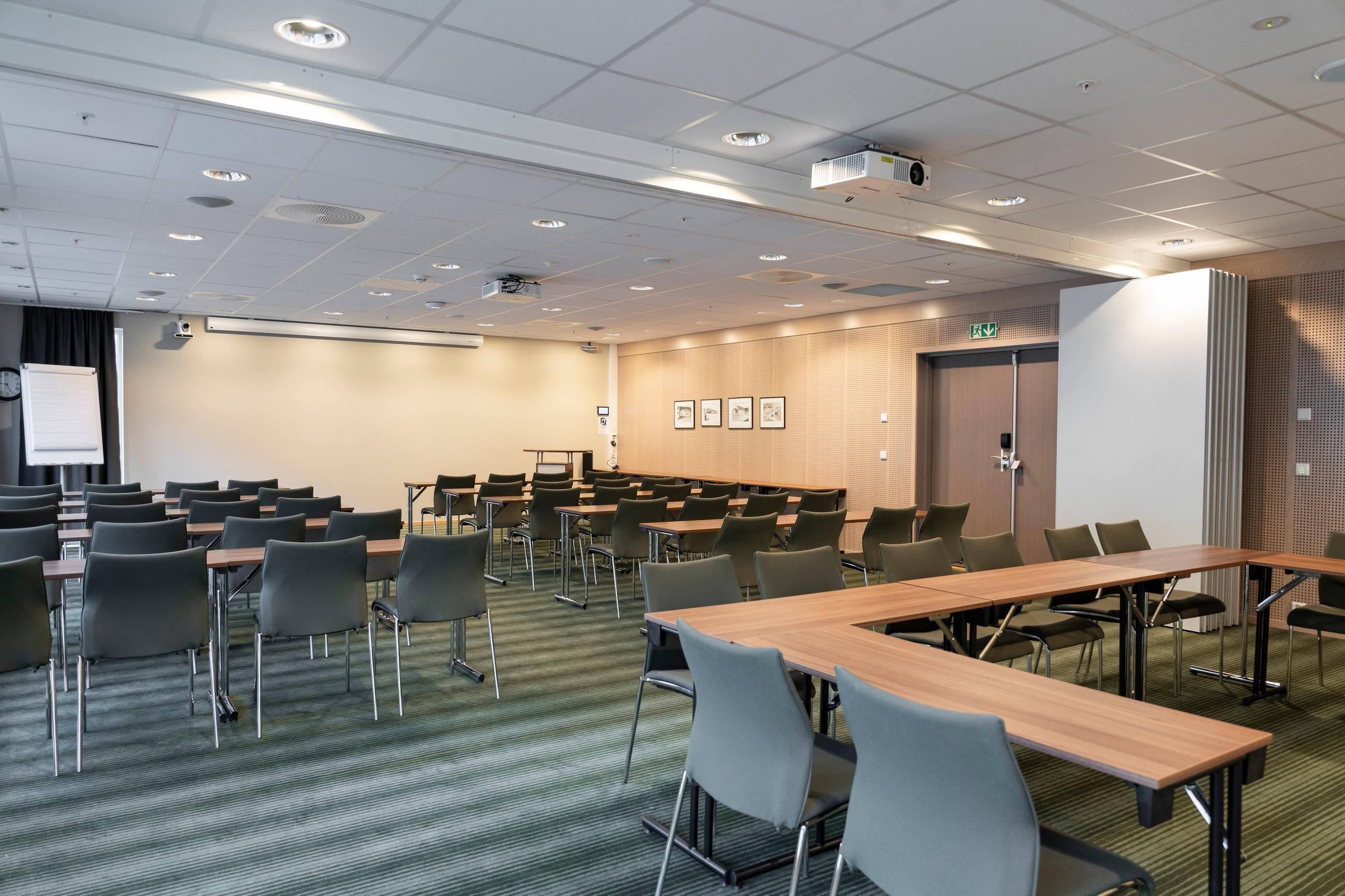 A conference room with multiple tables and chairs, a projector, and a whiteboard.