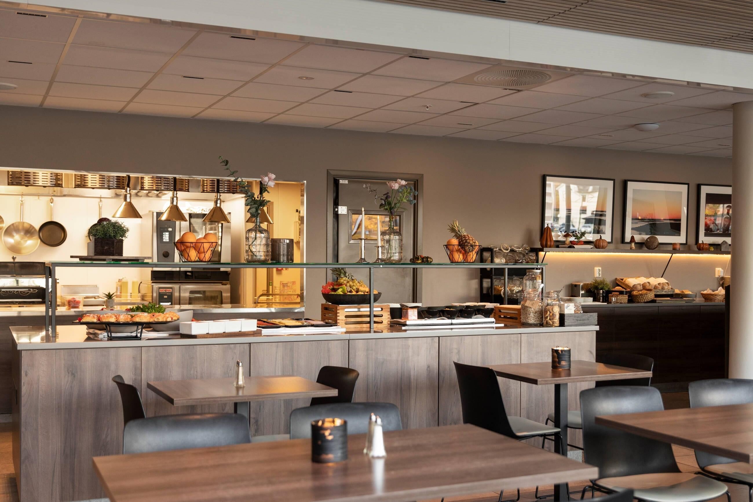 A modern restaurant with a central bar area, wooden tables, and chairs. - Home Hotel Helma (Mo-I-Rana)