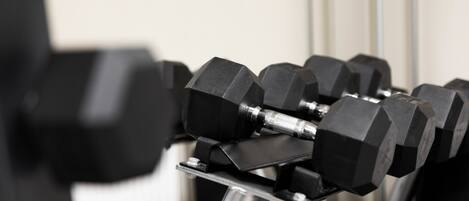 A close-up of a set of black dumbbells on a rack.