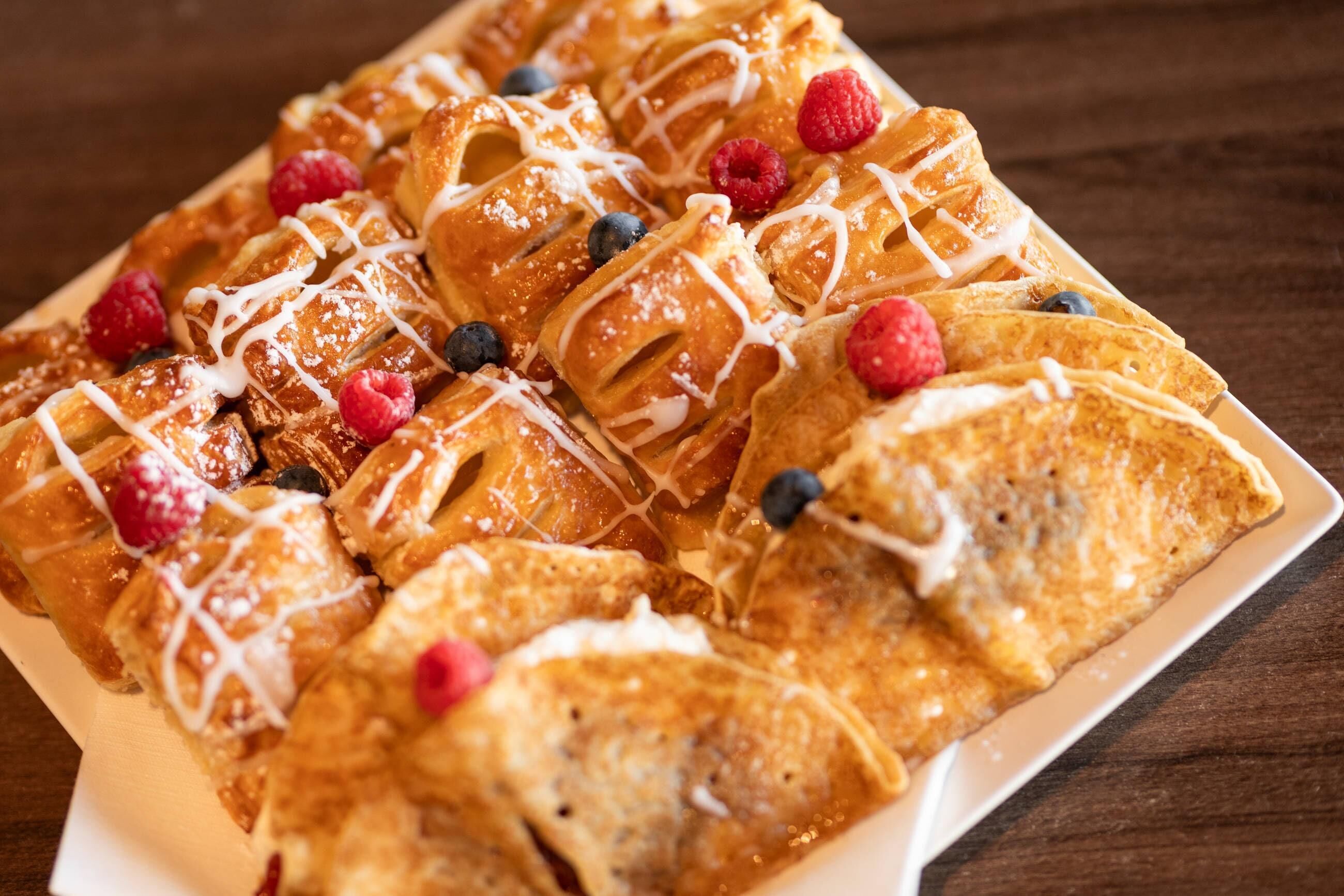 A plate of waffles with fruit and syrup.