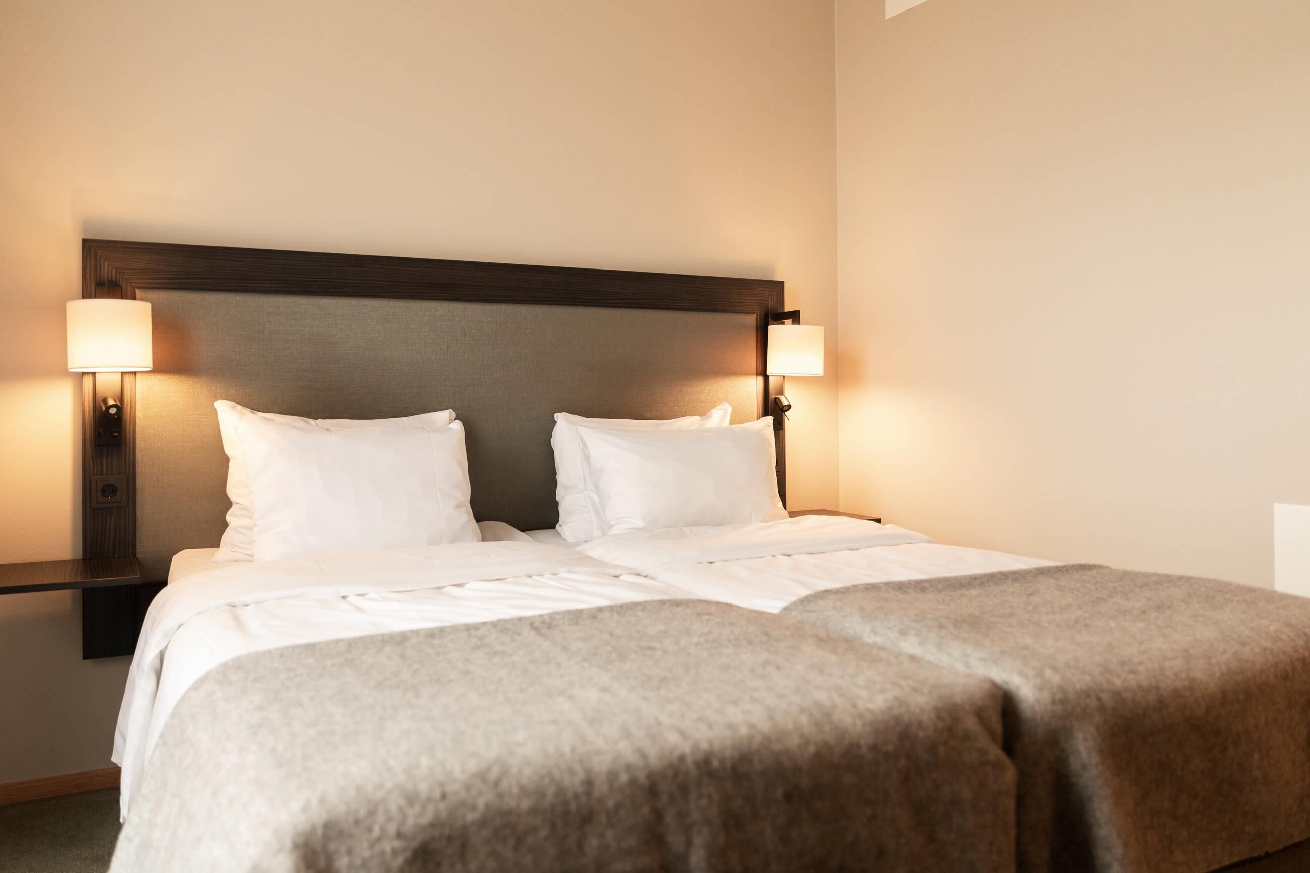 A double bed with a wooden headboard, two bedside lamps, and a neutral color scheme.