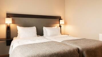 A double bed with a wooden headboard, two bedside lamps, and a neutral color scheme.