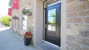 A stone building with a black door, red banners, and flower baskets. - Arrow Properties (North Grenville)