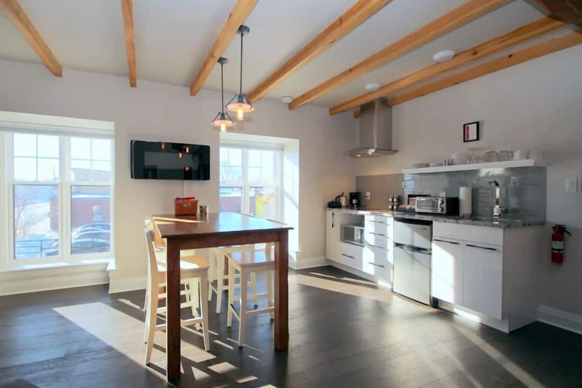 A modern kitchen with white cabinets, a wooden dining table, and a built-in oven.