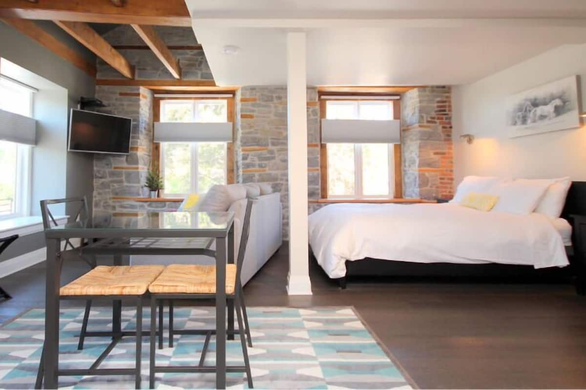 A modern bedroom with a bed, bedside table, and a TV mounted on the wall.