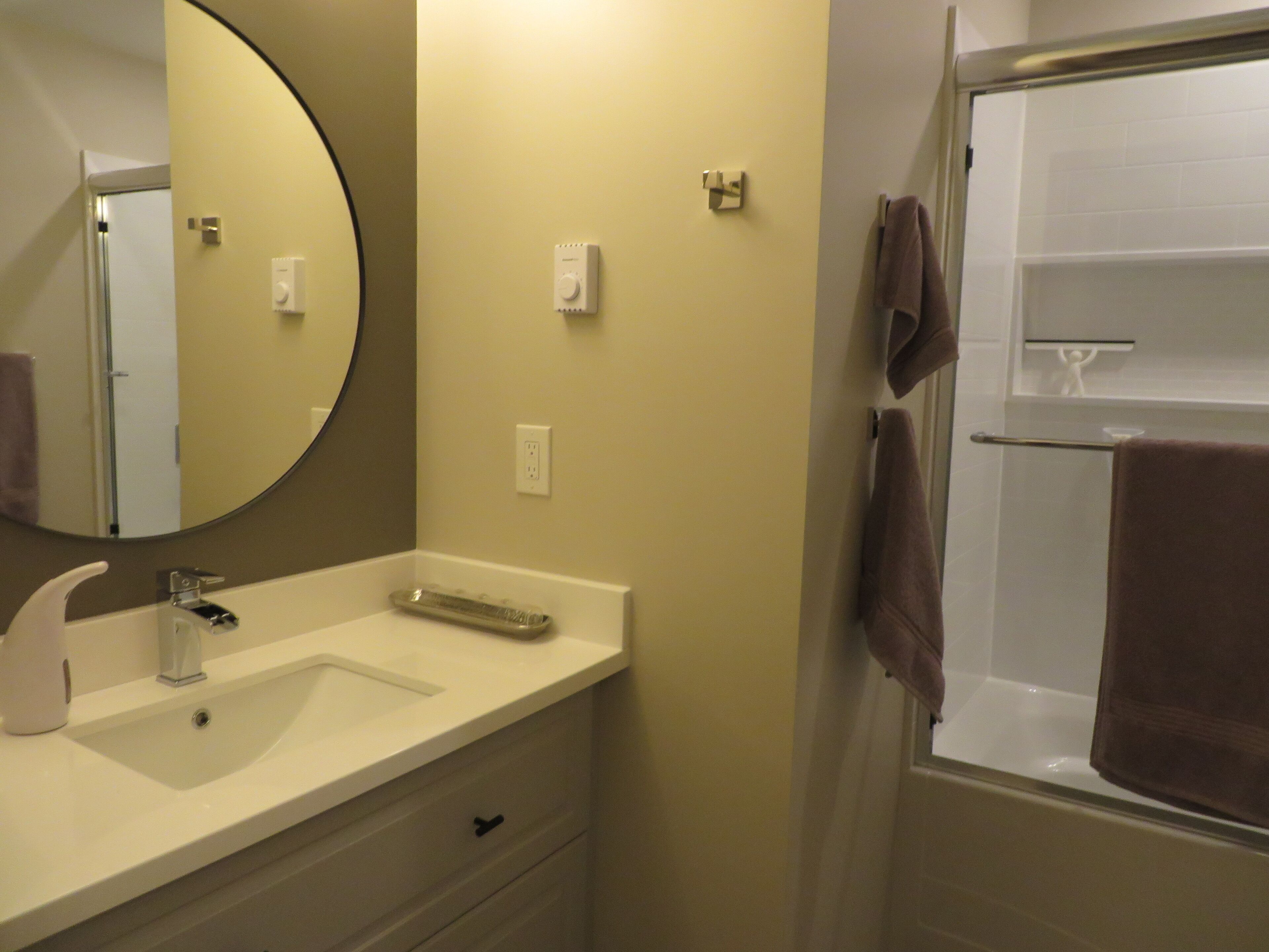 A bathroom with a sink, mirror, towel rack, and a shower area.