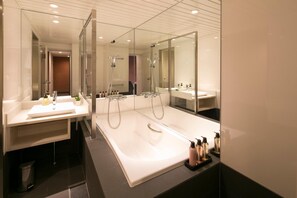 Un baño moderno con dos lavamanos, una bañera grande y un espejo.