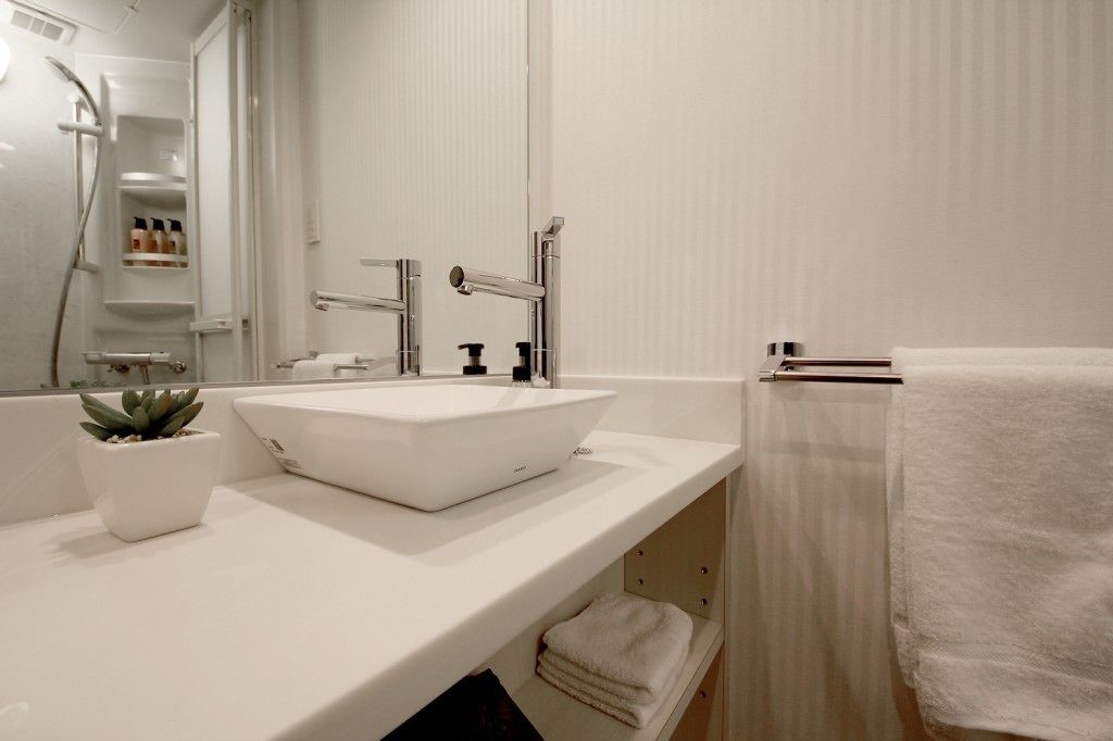 A modern bathroom with a white sink, a mirror, and a towel rack.