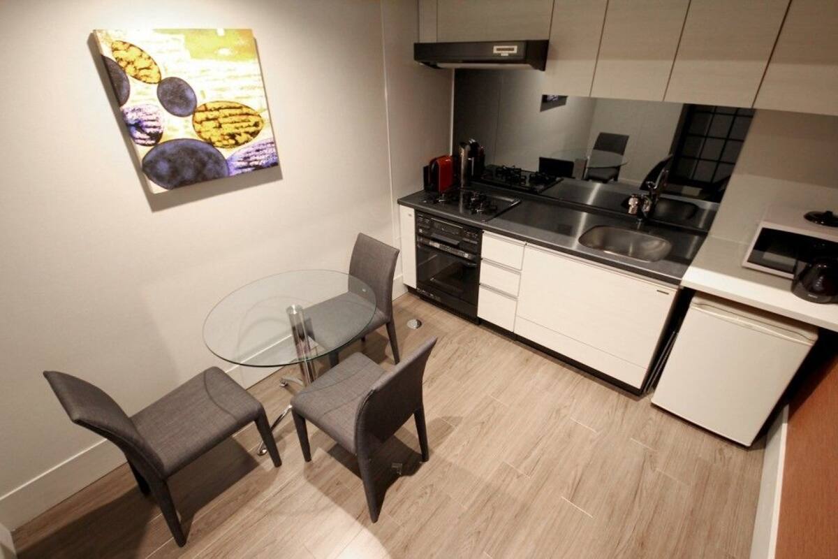 A compact kitchen with a modern design, featuring a gas stove, a sink, and a small refrigerator.