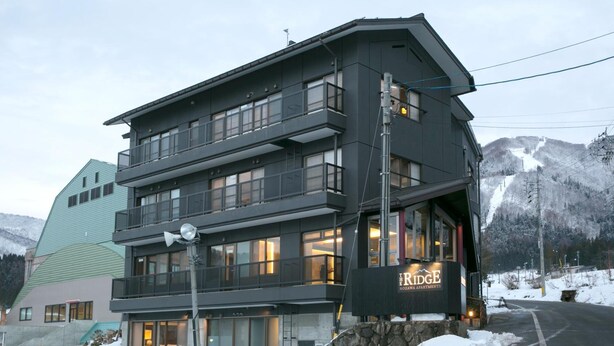 Monikerroksinen hotelli, jossa on parvekkeet, suuret ikkunat ja kyltti, jossa lukee: ”Ridge Notawa Apartments”.