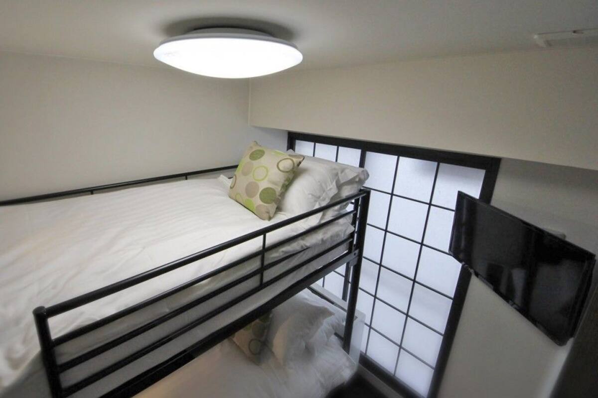 A bunk bed with a headboard, a pillow with a polka dot pattern, and a ceiling light fixture.