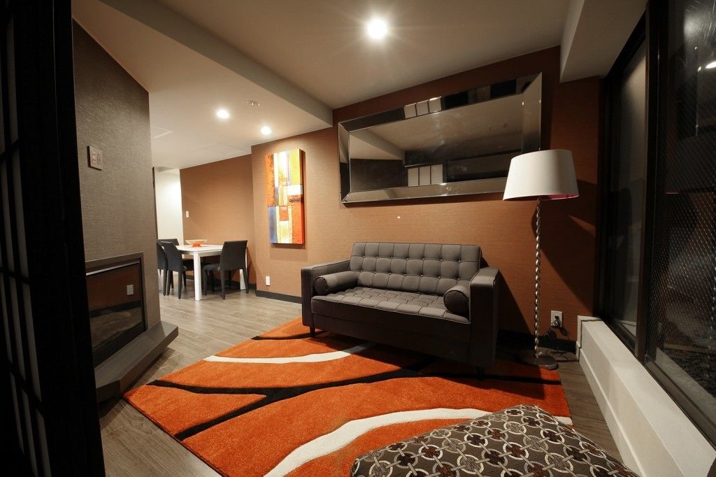 A modern living room with a grey sofa, a dining table, and a large mirror.