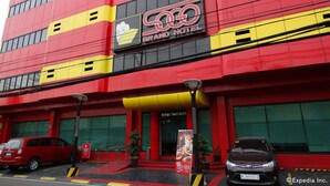 A hotel with a red and yellow facade, a prominent sign reading "GRAND HOTEL," and a visible entrance with a staircase. - Hotel Sogo EDSA Harrison (Pasay)